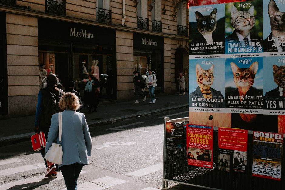 A bustling city street with pedestrians and vibrant posters on display.